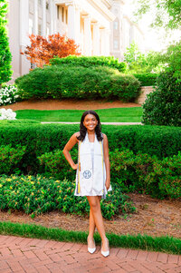 Senior wearing graduation swag smiling at camera during golden hour outside their university building