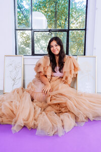 Singer-songwriter seated in a peach tulle dress for a soft editorial brand portrait