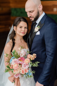 Bride holds bouquet and looks ahead while held by groom