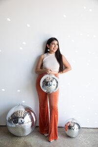 A woman posing in front of a wall with disco balls captured by an experienced Austin wedding photographer.