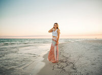 Senior portrait on the beach in Gulf Shores, Alabama — standing near the shoreline with her
hand in her hair.