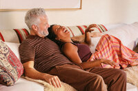 Couple laughing together on the couch at home, shot for Mochi's women's health vertical