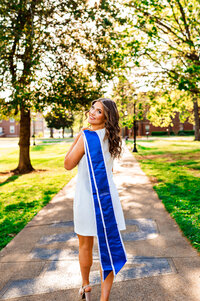 MTSU senior holding stole over shoulder and walking down the Raiders Walk beside the horseshoe