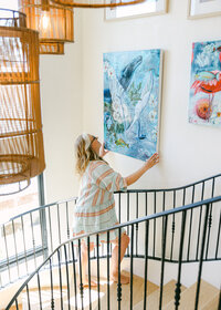 Personal brand photography of a mixed media artist installing artwork in her home studio in Southern California.