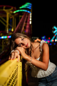 Senior portrait at the Greater Gulf State Fair in Mobile, Alabama — leaning on a yellow railing by
the Crazy Mouse roller coaster.