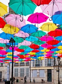 a collection of bright umbrellas hanging above head - Bloom by bel monili