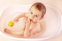toddler in bath with yellow rubber duck looking up