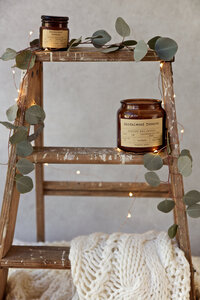 Styled product photography of soy candle displayed in a warm, home-inspired setting with natural textures and soft lighting