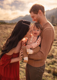Golden Hour family of 3 mommy kissing baby
