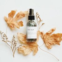 glass bottle of natural room mist on dried leaves