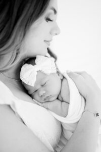 New mother holding tiny newborn during lifestyle photography session Miami