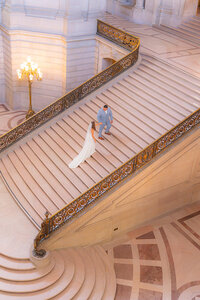 bride and groom walking up stairs at san francisco city hall wedding