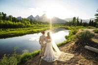 Bride and groom at Schwabacher's Landing in Grand Teton National Park, surrounded by mountain reflections and golden sunset light