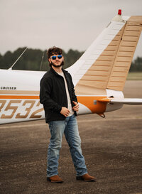 Senior portrait at a small hangar near Mobile International Airport in Mobile, Alabama — posing near airplane