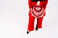 Playful full-body portrait of creative founder wearing a red suit in a bright studio setting.