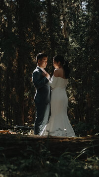 Bride and groom emjoying nature in a forest. Light beaming through the trees.