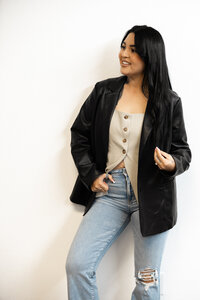 Woman with dark hair in casual outfit posing against white wall in studio. Photograph by Yucaipa branding photographer Kaitlyn Dawn Photography.