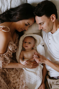 newborn baby being snuggled by parents