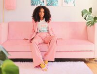 african american woman in pink suit on a pink couch posing for the camera