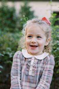 Toddler girl in a plaid dress with a peter pan collar laughing during her family portrait session in Menlo Park