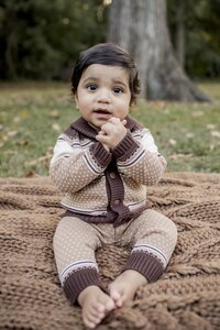 A one year old boy sitting on a blanket at a park in Allen, Texas