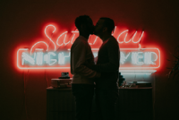 Couple kissing in front of neon sign