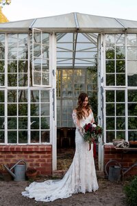 Bride standing in greenhouse doorway during wedding portraits