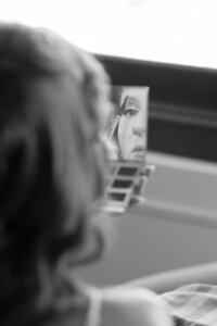 getting ready photo of bride applying makeup through a mirror for detroit wedding