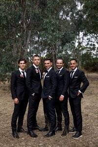 Groomsmen standing together outdoors during wedding party photos