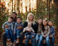 Blended family seated together on a park bench during fall family photography session