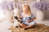 Toddler girl pets a live bunny during Easter Mini Session at Holy City Babies Portrait Studio in Charleton, SC.