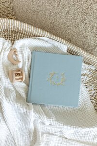 blue leather album with gold deboss laid in basket