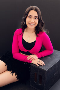 A female student from Oconomowoc High School poses in front of a black backdrop at our Downtown Waukesha photo studio.
