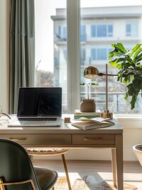 A modern home office with large windows overlooking an urban environment, designed for Amy Posner, a creative freelancer and business coach.