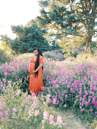 Mom looking down at her pregnant belly surrounded by sweet pea flowers