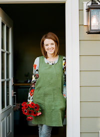Kennedy Occasions founder, Emily Kennedy, smiles in doorway holding red bouquet