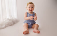 Baby smiles at the camera during Baby Milestone Portrait Session at Holy City Babies Portrait Studio in Charleston, SC.