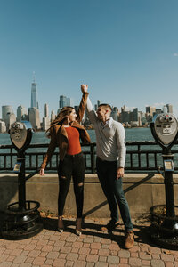 man and woman holding hands with city in background