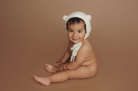 newborn in knit cap, brown backdrop during studio portrait session in North Hollywood