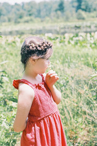 film image of girl in red dress smelling wildflower by richmond family photographer