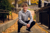 A Waukesha North High School student squats on a bridge at Retzer Nature Center for his senior pictures.
