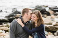 Couple laughing on the rocks at Narragansett Beachduring engagement session