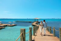 Couple walking hand in hand on a scenic dock over turquoise waters, perfect for romantic getaways.