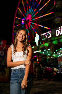 Senior portrait at the Greater Gulf State Fair in Mobile, Alabama — posing with a lit Ferris wheel
behind her.