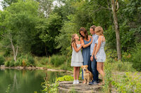A family and their dog hugging each other and standing on a rock overlooking a quarry in West Bend Wisconsin