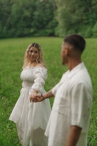 Engaged couple swaying arms in a field in Pigeon Trail near Kennesaw Mountain.
