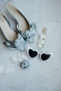 Flatlay with bridal shoes and heart sunglasses