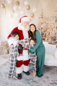 santa claus smiles with siblings in matching christmas pajamas