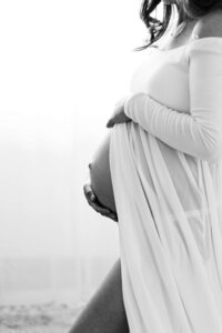 Mother‑to‑be cradling her belly during a quiet moment at home in Bend.