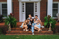 Teen siblings sitting together on brick front steps during a family photography session in New Bern